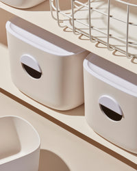 A close-up image of the Cream Medium Storage Bins with other Open Spaces items on a cream background.