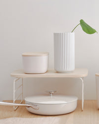 The Small Cream Storage Bin with a wooden lid on a shelf riser.