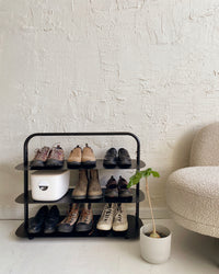 The Open Spaces Black Entryway Rack on a white background with shoes displayed on it.