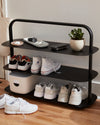 The Open Spaces Black Entryway Rack on a gray background with shoes displayed on it.