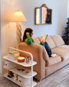 A girl sitting in her living room with the Open Spaces Entryway rack on the side.