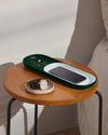 The Open Spaces Dark Green Nesting Tray with jewellery, watch and a phone on a bedside table.