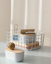 A close-up image of 2 Light Blue Storage Bins with Wooden Lids and a Large Basket on a white countertop.