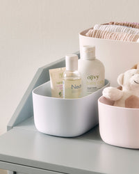 Close up view of the Storages Bins with beauty products on a cream background.