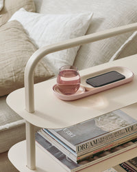 The Open Spaces Pink Nesting Tray with water and a phone on it on a cream entryway rack.