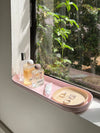 The Open Spaces Pink Nesting Tray with perfumes and Jewellery on a window sill.