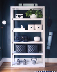 Two Open Spaces Cream Medium Storage Bins with wooden lids and Two Navy Medium Storage baskets on a cream stand.