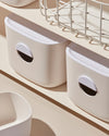 Close up of two Cream Medium Storage Bins on a cream surface. 