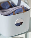 Close up of the Light Blue Medium Storage bin with cloths in it.