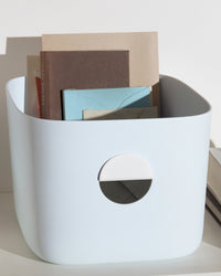 Close up of the Light Blue Medium Storage bin with books in it on a white background.