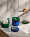 The Blue & Dark  Storage gems with beauty products stored in it on a marble surface. 