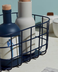 A close up of the Open Spaces Navy Medium Wire Basket with bottles inside it.