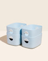 Four Open Spaces Medium Light Blue Storage Bins on a cream background. 