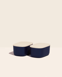 Two Small Navy Storages Bins with wooden lids on a cream background.