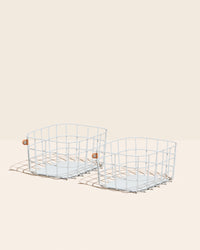 Two Open Spaces Light Blue Wire Baskets on a cream background. 